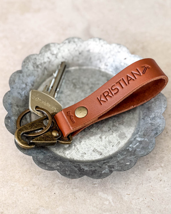 HOOK nøglering i cognacfarvet læder graveret "KRISTIAN" med flysymbol, med nøgle i en metalskål