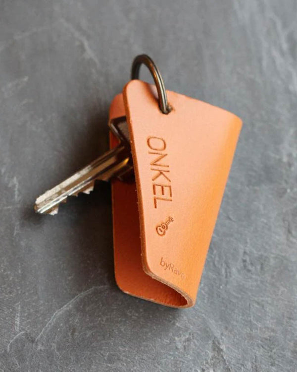 FOLD nøgleskjuler i cognac læder med graveringen "Onkel" og lille guitar, med nøgler på mørk skifer