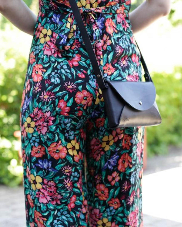INA skuldertaske i sort læder båret crossbody til blomstret buksedragt i haven