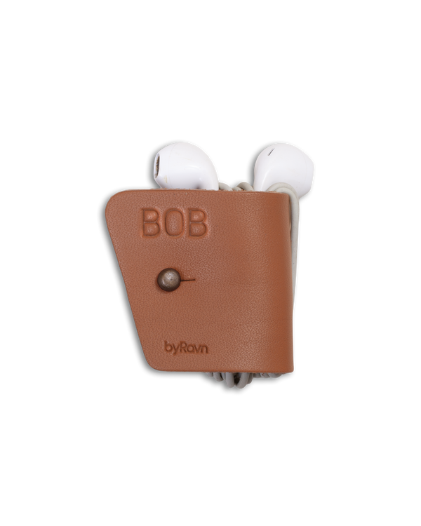 KAX høretelefonholder fra byRavn i cognac læder med geværknap i antik messing og navnet "Bob" graveret, med earpods