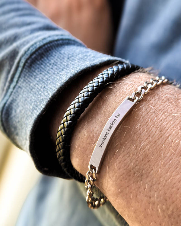 ARA armbånd i sølvfarvet rustfrit stål med graveringen "Verdens bedste far" om håndleddet, båret sammen med RAY flettet læderarmbånd