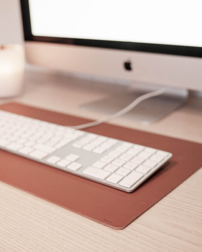 DESK skriveunderlag i cognac læder under hvidt tastatur foran iMac på lyst træskrivebord