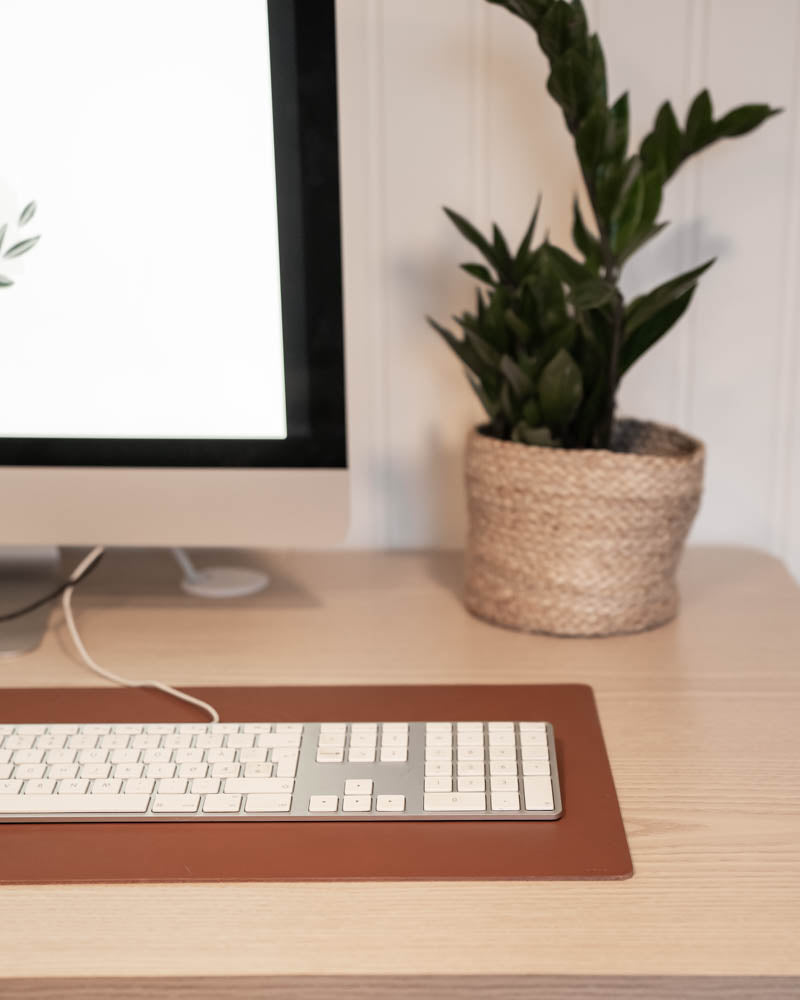 XXL DESK skriveunderlag i cognac læder under tastatur foran iMac med grøn plante i fletkurv