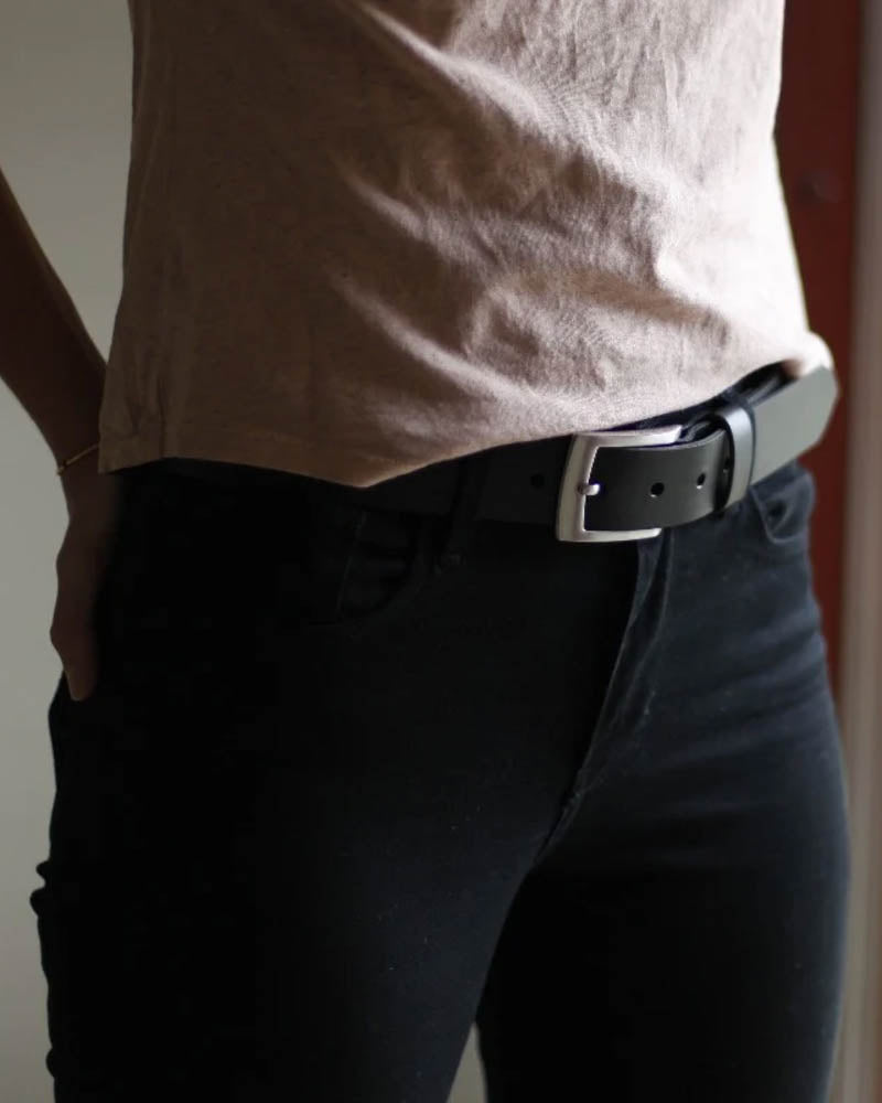 EDGE bælte i sort læder båret af kvinde i sorte bukser og beige t-shirt, set fra siden