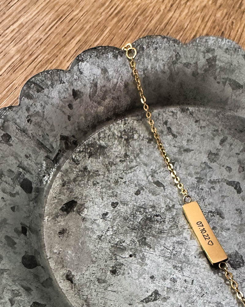 EVI armbånd i guldbelagt stål med datoen "07.10.22" ♡ graveret på aflang plade, liggende på zinkfad
