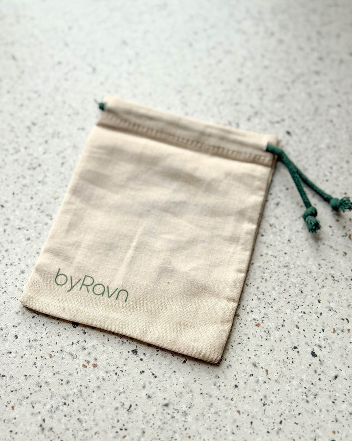 Gavepose i hvidt stof med byRavn-logo og grøn snor
