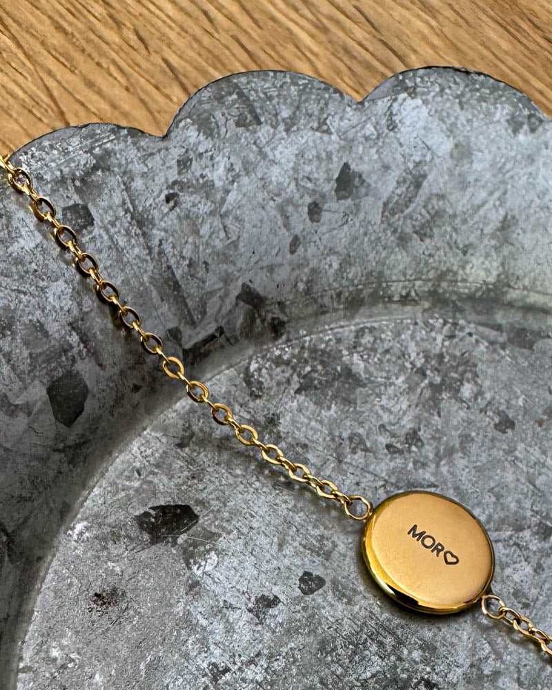 IBI QUOTE armbånd i guldbelagt stål med graveringen "Mor" ♡ på rund plade, liggende på zinkfad