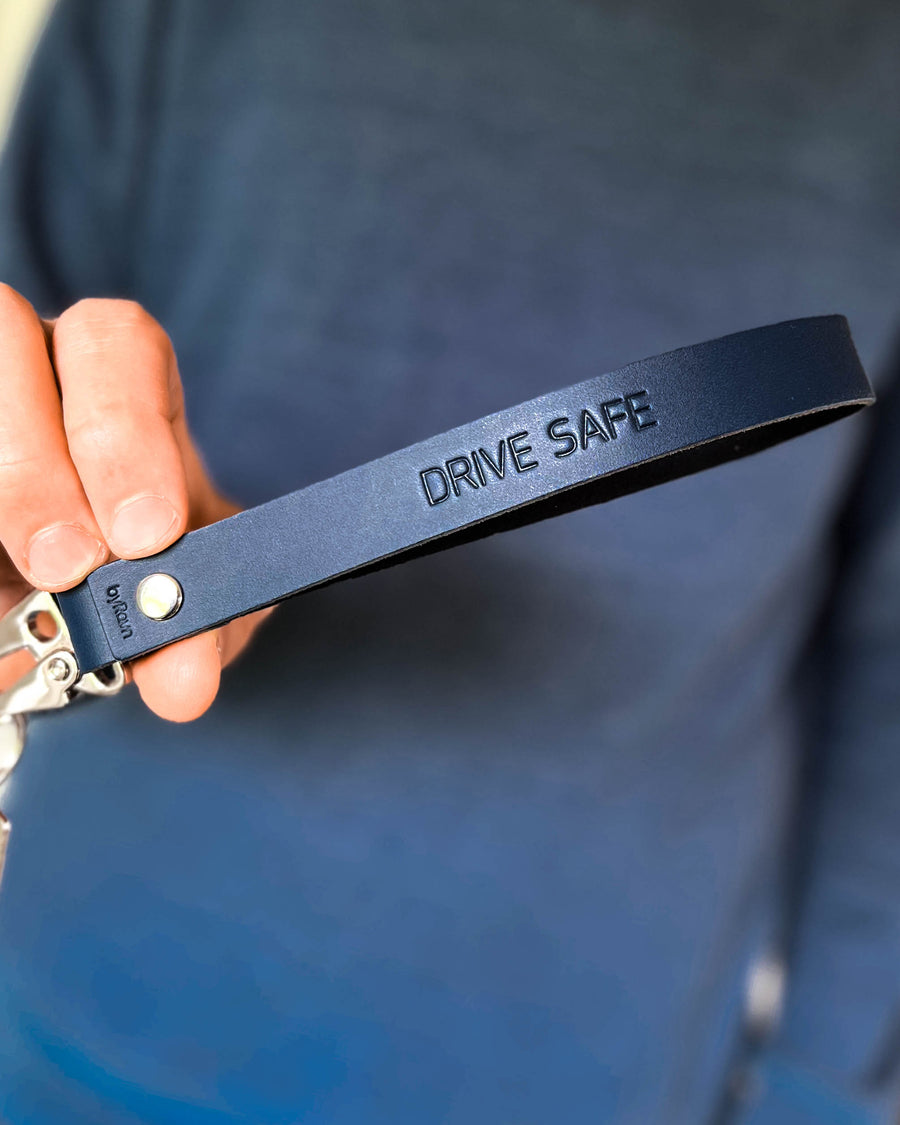 IRON nøglering i mørkeblå læder med lang strop og graveringen "Drive safe", holdt i hånden