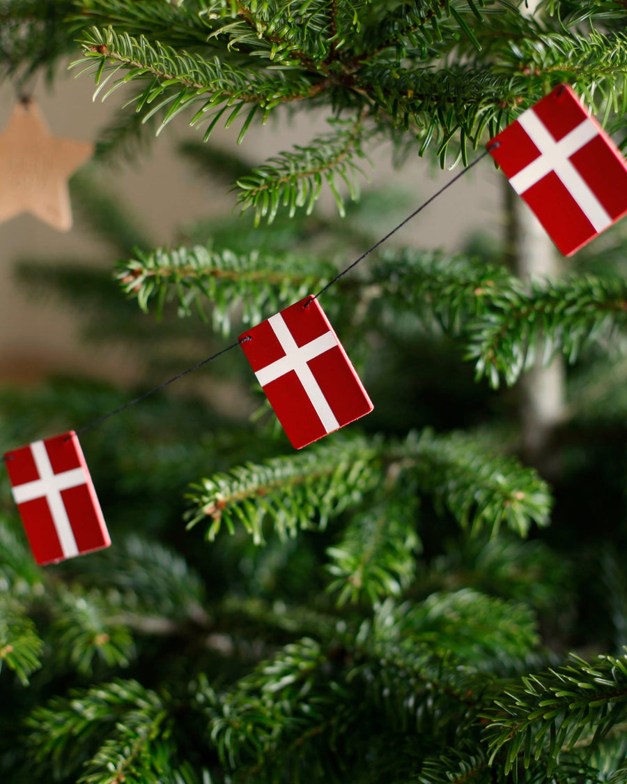 SALUT flagranke med Dannebrog-flag i læder hængt som julepynt i grønt juletræ med træstjerne