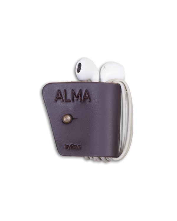 KAX clips til høretelefoner fra byRavn i mørkebrunt læder med høretelefoner viklet om og graveringen "Alma"