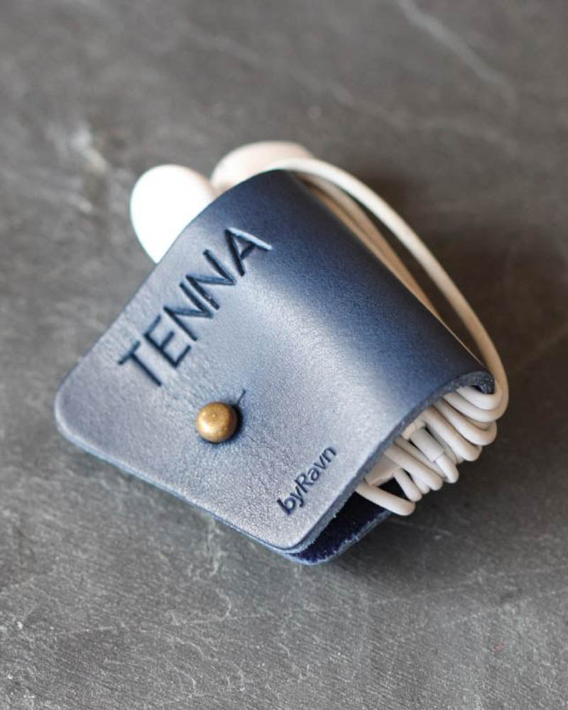 KAX høretelefon-clips i mørkeblåt læder med personlig gravering "Tenna" og ledning viklet om, på mørk skifer