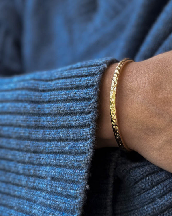 LUNA armbånd i guldbelagt stål, hamret armring båret om håndleddet til blå strik