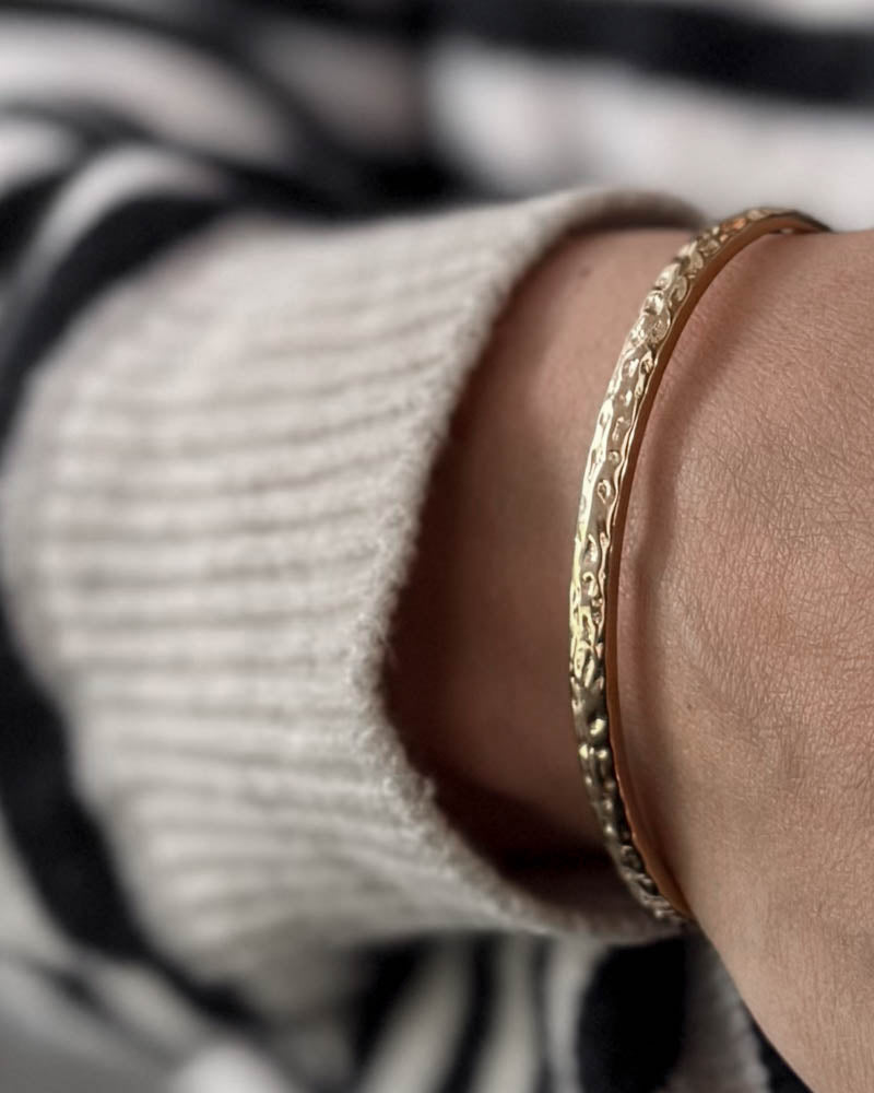 LUNA armbånd i guldbelagt stål med hamret overflade om håndleddet, hvid strik og stribet bluse