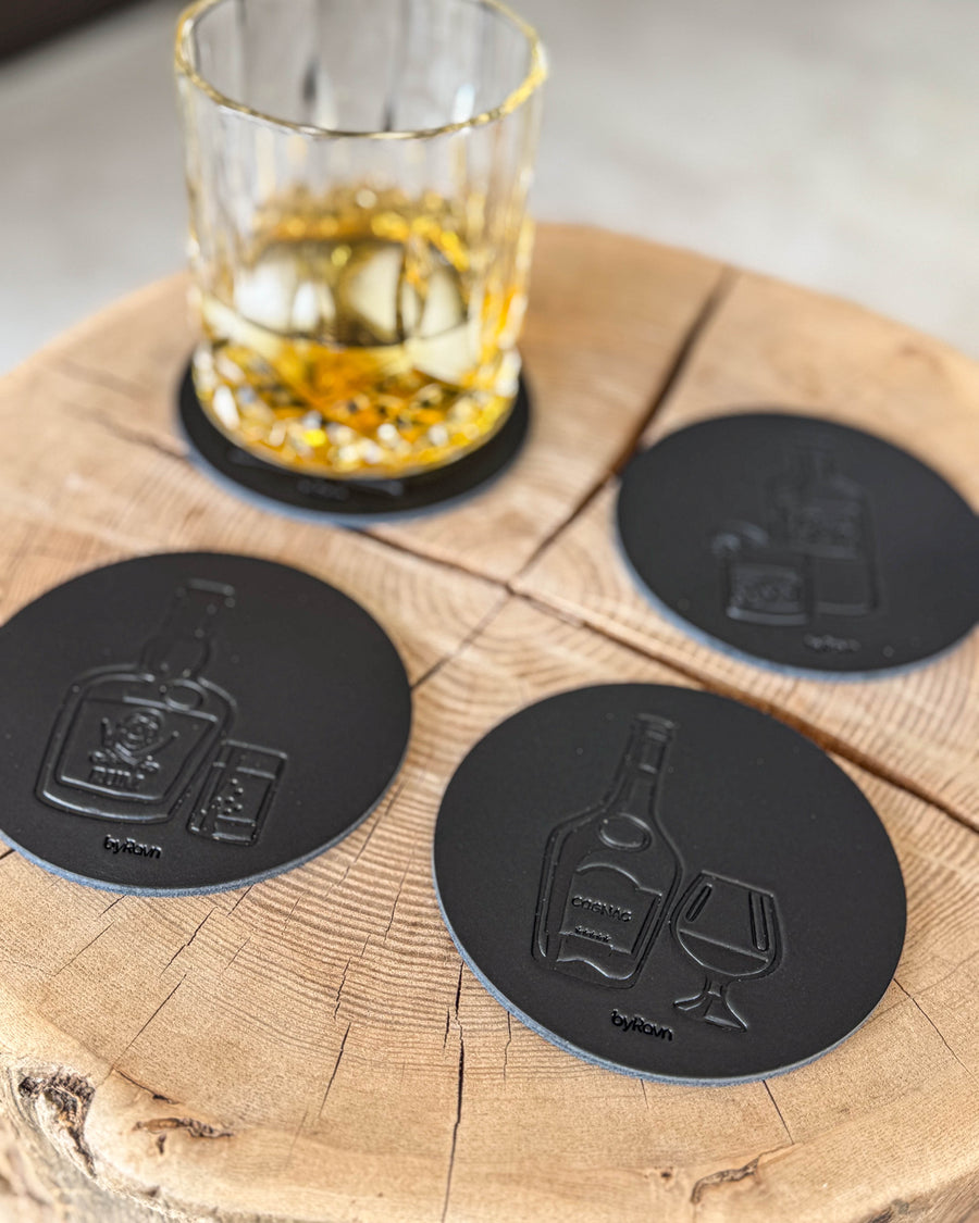 MOKKA spiritus bordskånere i sort læder præget med rom, cognac og gin på træskive ved krystalglas med whisky