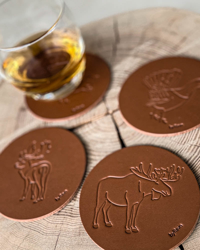 MOKKA jagt bordskånere i cognac læder præget med elg, dådyr og tjur på træskive ved glas med whisky