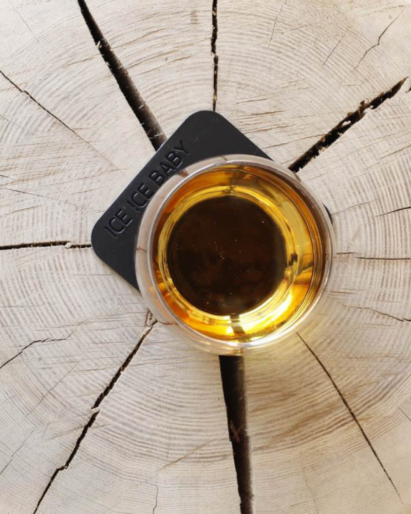 MOKKA firkantet bordskåner i sort læder med graveringen "Ice ice baby" under whiskyglas på træskive set ovenfra