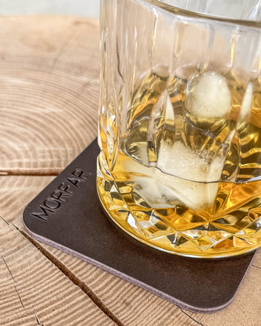 MOKKA firkantet bordskåner i mørkebrunt læder med graveringen "Morfar" under krystalglas med whisky og is