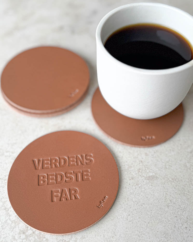 MOKKA bordskånere i cognac læder præget "Verdens bedste far" på lyst bord med hvid kaffekop