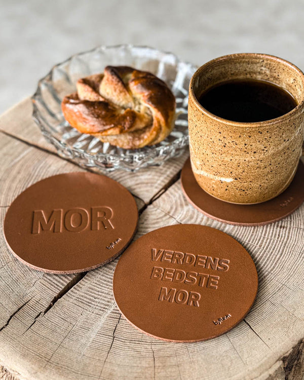 MOKKA bordskånere i cognac læder præget "Mor" og "Verdens bedste mor" på træskive med kaffekop og kanelsnegl
