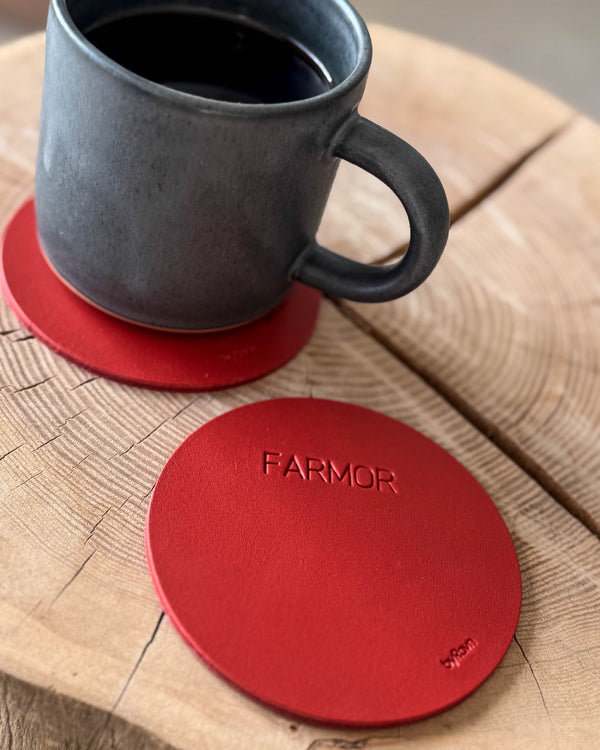 MOKKA rund bordskåner i rødt læder med graveringen "Farmor" på træskive, grå kaffekop på coaster bagved