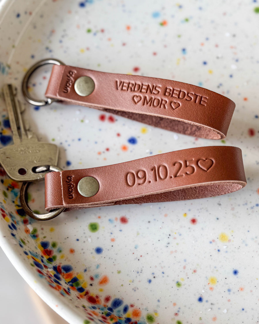 RAVN nøgleringe i cognac læder med graveringen "Verdens bedste mor" og datoen "09.10.25" ♡ i prikket keramikskål med nøgler