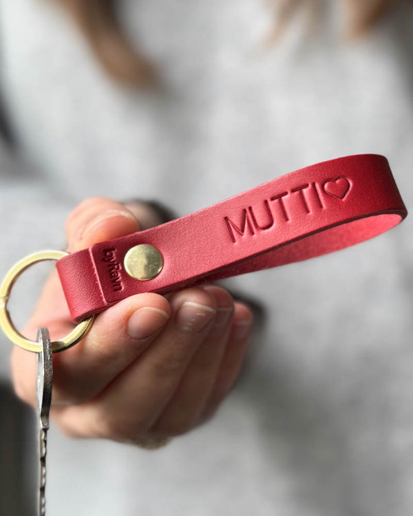 RAVN nøglering i rødt læder med personlig gravering "Mutti" ♡ og messingnitte, holdt i hånden med nøgle