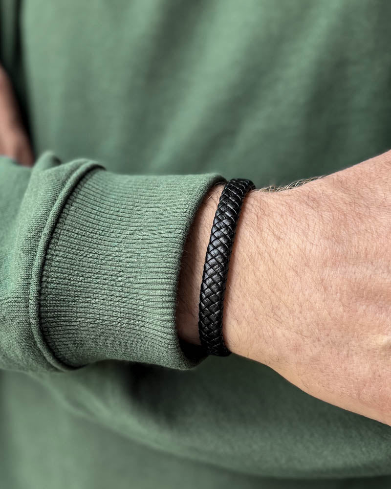 RAY læderarmbånd i sort flettet læder båret om mandehåndled, grøn sweatshirt