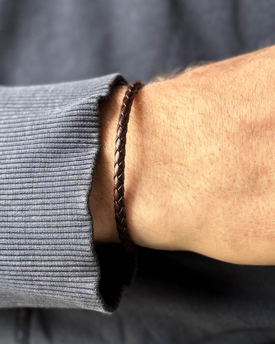 RIO læderarmbånd i mørkebrunt flettet læder om mandehåndled, blågrå sweatshirt