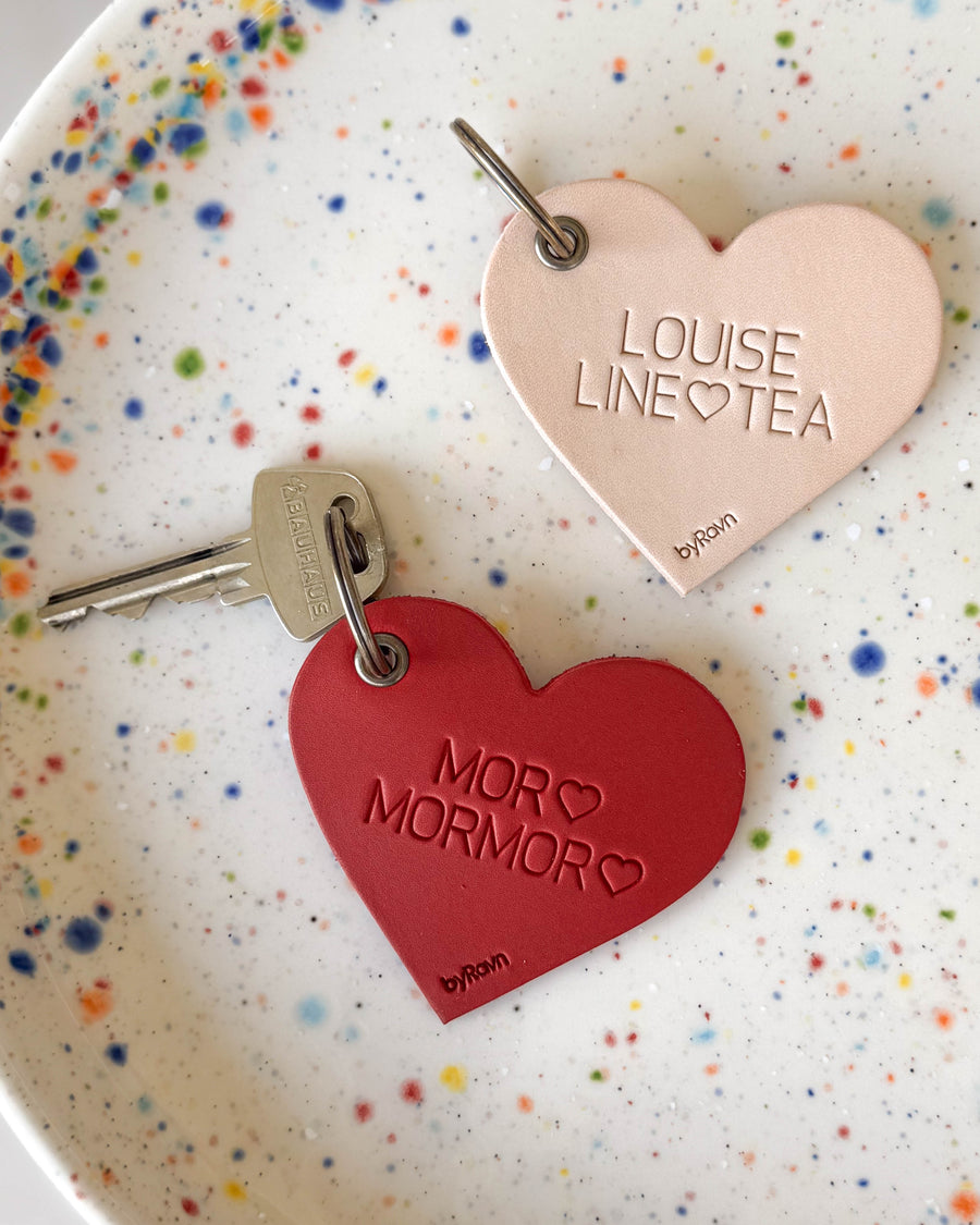 ROSE hjerte-nøgleringe i naturfarvet og rødt læder med graveringerne "Louise Line ♡ Tea" og "Mor ♡ Mormor ♡" på prikket tallerken