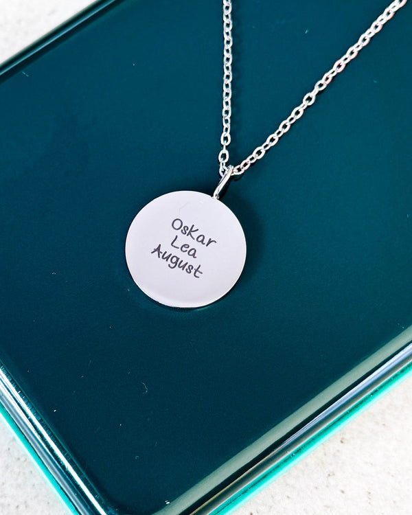 SIA QUOTE SCRIPT navnehalskæde i sølvfarvet rustfrit stål med navnene "Oskar Lea August" i håndskrift, på grøn glasæske