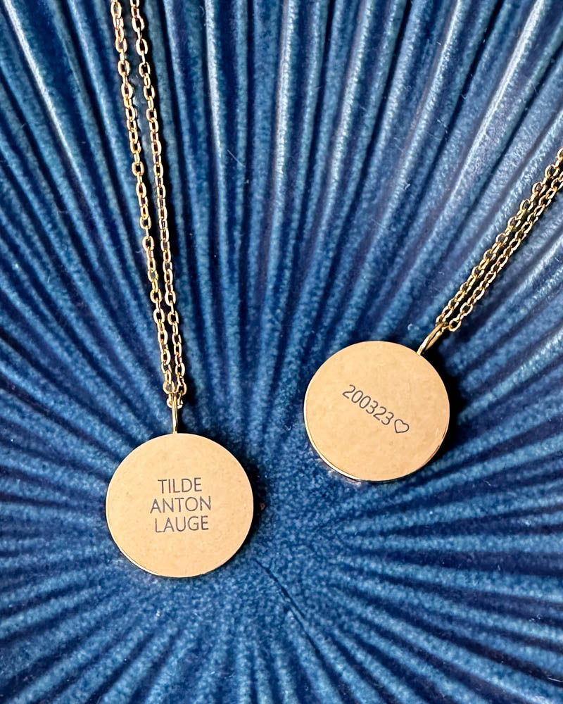 SIA QUOTE navnehalskæde i guldbelagt stål, to vedhæng graveret "Tilde Anton Lauge" og "200323" ♡, på blå riflet skål