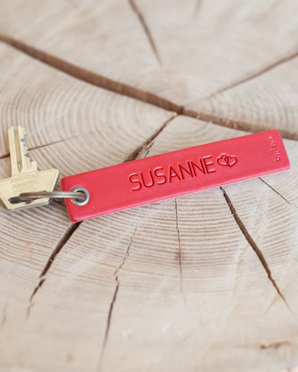 SOLO Medium nøglering i rødt læder med navnet "Susanne" og to hjerter graveret, med nøgle på træskive