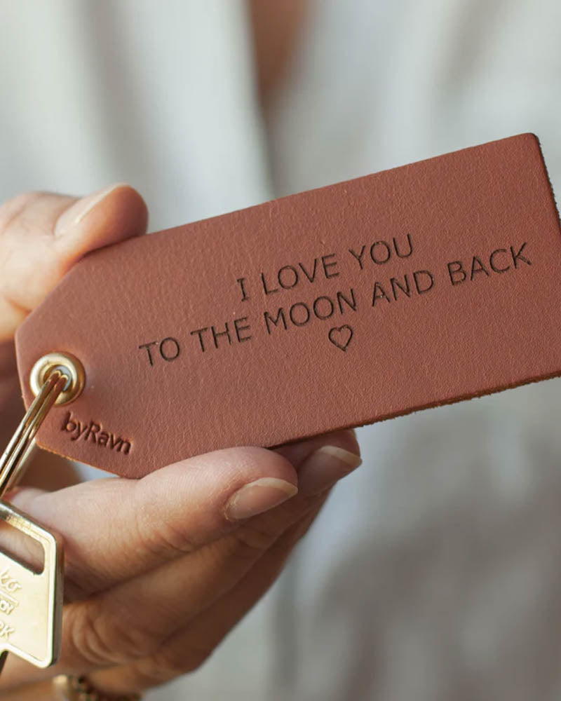 STORM nøglering i cognac læder holdt i hånden med nøgle og graveringen "I love you to the moon and back" ♡