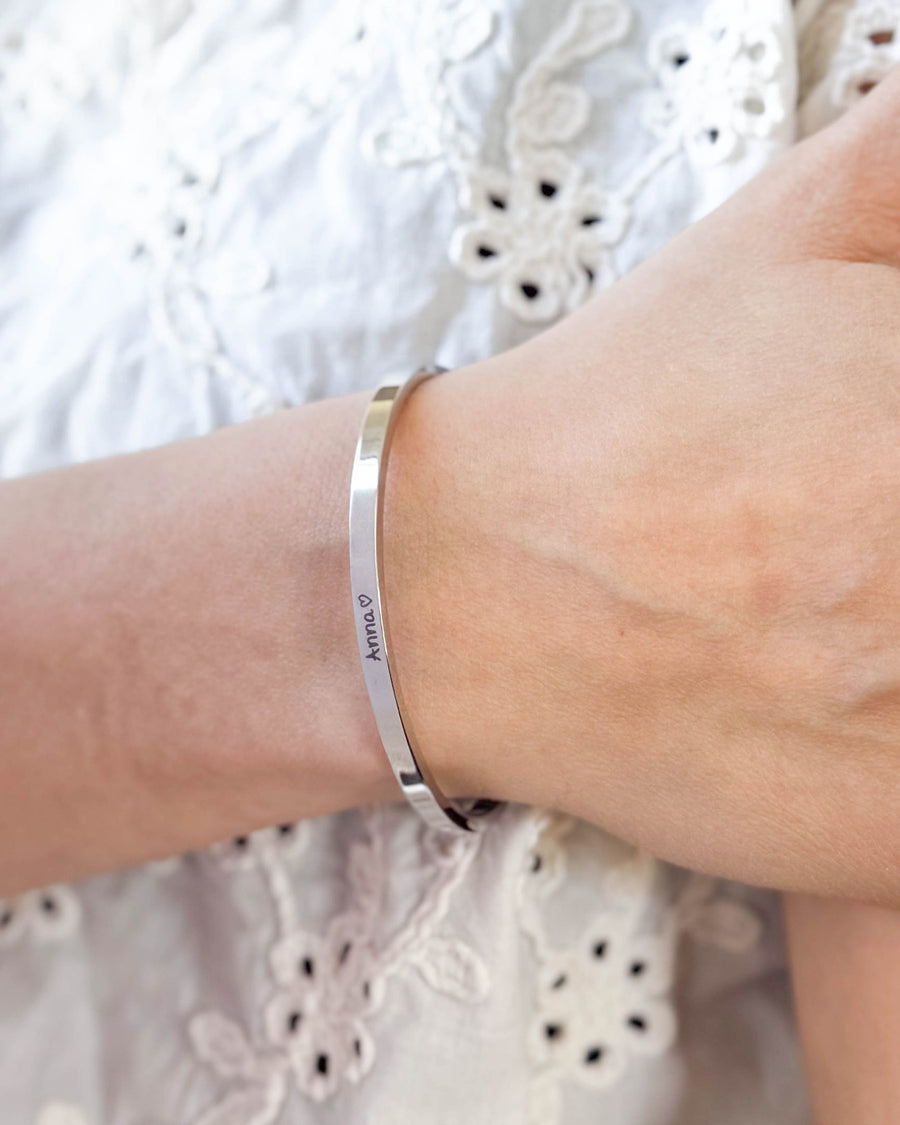 VENUS SCRIPT armbånd i sølvfarvet rustfrit stål med navnet "Anna" ♡ i håndskrift om håndleddet, hvid broderet bluse