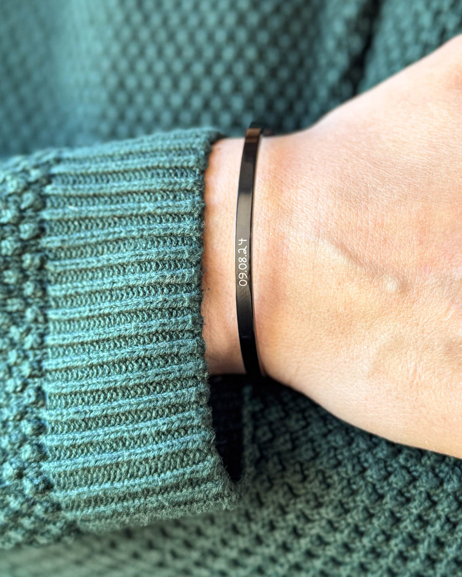 VENUS SCRIPT armbånd i sort stål med datoen "09.08.24" i håndskrift om håndleddet, grøn strik