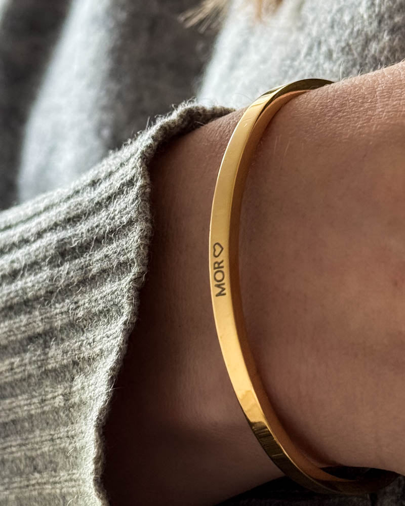 VENUS armbånd i guldbelagt stål med personlig gravering "Mor" ♡ båret til grå uldstrik