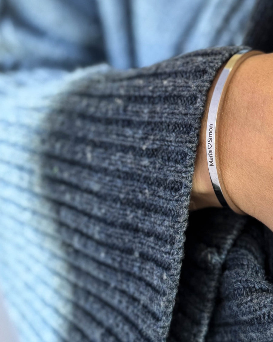 VENUS armbånd i sølvfarvet rustfrit stål med graveringen "Maria ♡ Simon" om håndleddet, blå strik